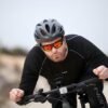 A cyclist wearing professional high-performance sports goggles while riding a bike outdoors.